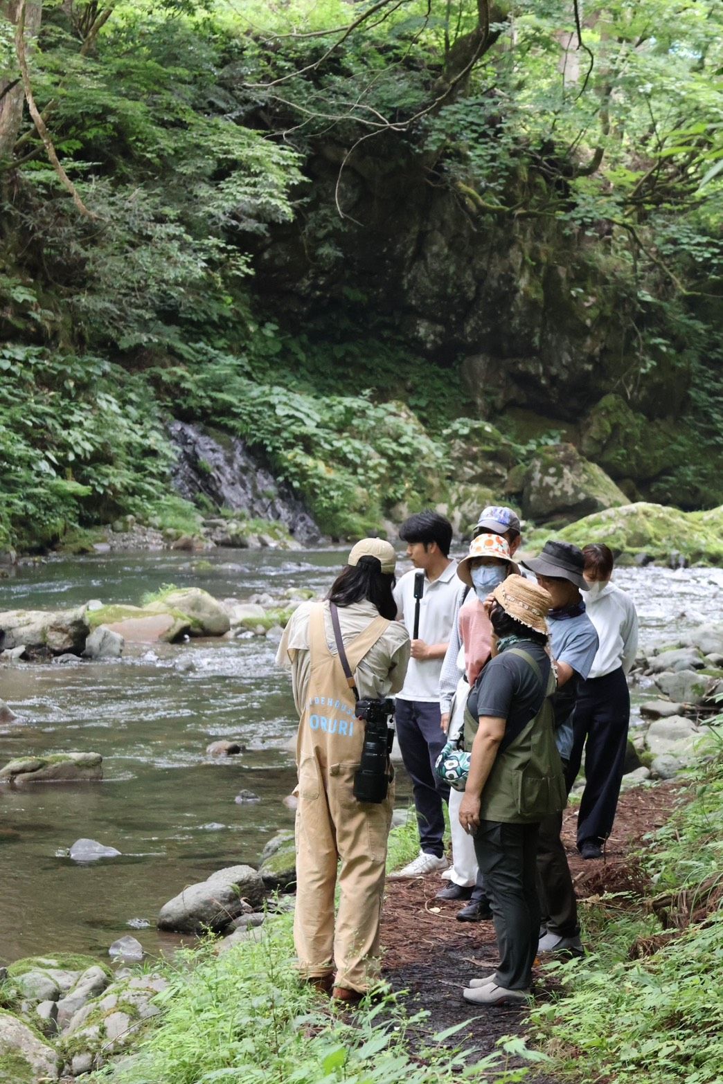 足羽川の川辺で参加者と一緒に生き物を探すガイド